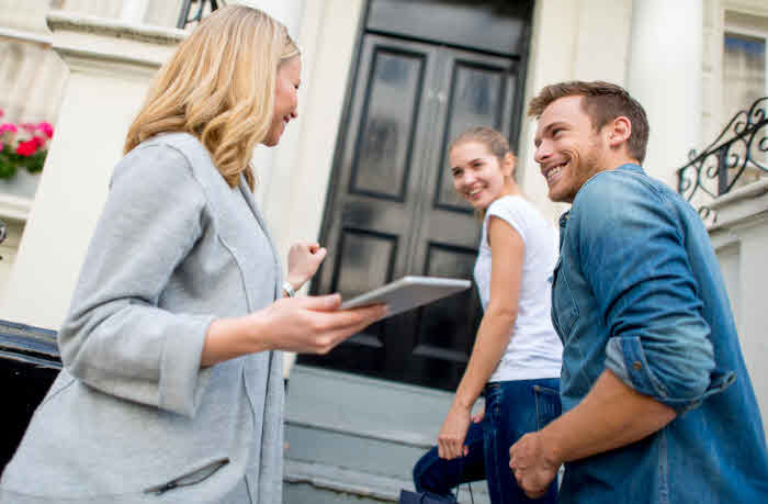 couple walking into house with realtor