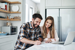 Couple signing papers at kitchen counter